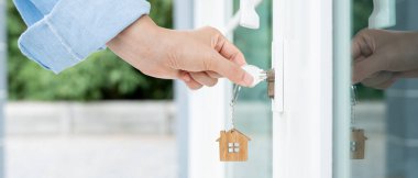 Evin kilidini açmak için ev sahibi anahtarı kapıya takılı. Kira ve satış için ikinci el ev. Sahibi yeni ev, satın al, sat, yenile, yatırım, sahip, mülk