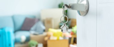 Moving house, relocation. The key was inserted into the door of the new house, inside the room was a cardboard box containing personal belongings and furniture. move in the apartment or condominium