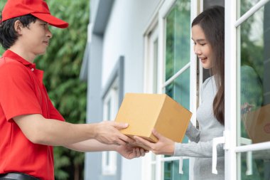 Happy smiling woman receives boxes parcel from courier in front house. Delivery man send deliver express. online shopping, paper containers, takeaway, postman, delivery service, packages