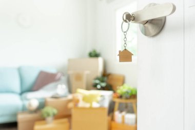 Moving house, relocation. The key was inserted into the door of the new house, inside the room was a cardboard box containing personal belongings and furniture. move in the apartment or condominium