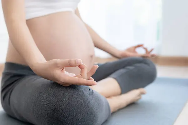 Pregnant Woman Doing Yoga On Exercise Mat. meditating for near-term childbirth of meditating attractive Pregnant female recreation and relax, breathing and calm with yoga. Self Care