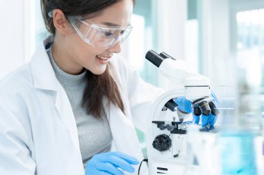 Bilimadamı ileri bilimsel laboratuvarda biyokimyasal örnekleri analiz ediyor. Tıbbi profesyonel kullanım mikroskobu virüsün mikrobiyolojik gelişimini gösteriyor. Fen laboratuvarında biyoteknoloji araştırması.