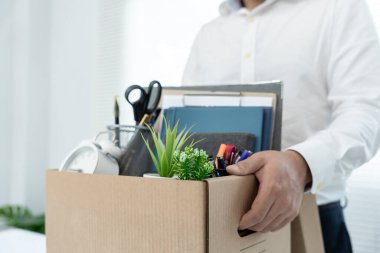 Stresli iş adamları şirketten istifa edecek. İçinde kişisel eşyalar olan kahverengi bir karton kutuyu kaldırıyor. İstifa, iş yerleştirme ve boşluklar kavramı.