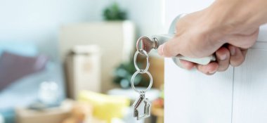 Taşınmak, taşınmak. Anahtar yeni evin kapısına yerleştirilmiş, odanın içinde kişisel eşyalar ve mobilyalar içeren bir karton kutu vardı. Daireye gir, afiş.