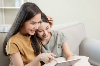 LGBT grubu. Güzel görünümlü lezbiyen çiftler tatilde evde tablet kullanır. Asyalı genç çift birbirlerine mutlu bir şekilde sarılıyorlar, aşık, biseksüellik, homoseksüellik, özgürlük, ifade, mutlu hayat.