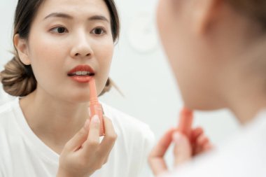 Portre güzel Asyalı kadın aynanın karşısına oturur ve makyaja gülümser. Sağlıklı bir kadının yüzü makyaj yapar. Reklam, yaşam tarzı, kozmetik, makyaj malzemeleri, güzellik etkinliği, güzellik uzmanı.