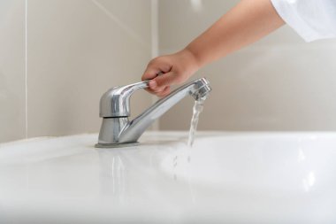 Su tasarrufu. Küçük çocuk çevreyi korumak için tuvaletteki suyu kapatıp duruyor. Yeşillenen gezegen, küresel ısınmayı azalt Dünya 'yı, yaşamı, geleceği, risk enerjisini, krizi, su gününü kurtar.