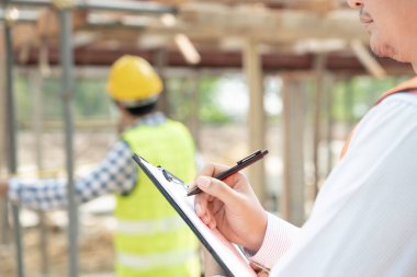 inspector or engineer is inspecting construction and quality assurance new house using a checklist. Engineers or architects or contactor work to build the house before handing it over to the homeowner