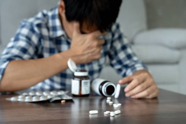 Asyalı erkek aşırı dozda hap kullanıyor, stresli, üzgün, uyuşturucu bağımlısı, uyuşturucu bağımlısı, hasta, sağlıksız, mutsuz, intihar, depresyonda veya umutsuz, uyuşturucu bağımlısı, yaşam ve aile sorunları, motivasyonsuz