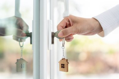 Evin kilidini açmak için ev sahibi anahtarı kapıya takılı. Kira ve satış için ikinci el ev. Sahibi yeni ev, satın al, sat, yenile, yatırım, sahip, mülk
