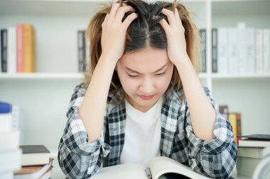 Asian student woman have anxiety because of exams, female prepare for test and learning lessons in the library. stress, despair, haste, misunderstanding reading, discouraged, expectation, knowledge