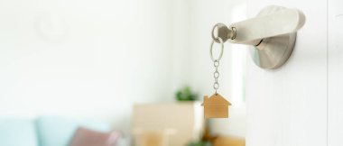 Taşınmak, taşınmak. Anahtar yeni evin kapısına yerleştirilmiş, odanın içinde kişisel eşyalar ve mobilyalar içeren bir karton kutu vardı. Daireye gir, afiş.