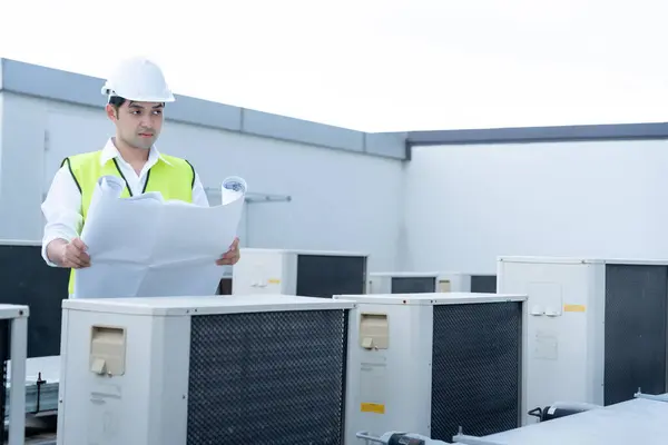Asian maintenance engineer works on the roof of factory. contractor inspect compressor system and plans installation of air condition systems in construction. Blueprint, inspector, control