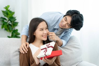 Asian couples are about to do a surprise with their wives on their wedding anniversary. Teenage husband and wife after marriage. Happiness and smiles and laughter in warm family. cuddling, warm hugs