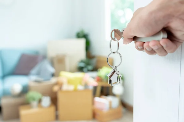 Moving house, relocation. The key was inserted into the door of the new house, inside the room was a cardboard box containing personal belongings and furniture. move in the apartment or condominium