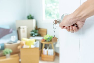 Moving house, relocation. The key was inserted into the door of the new house, inside the room was a cardboard box containing personal belongings and furniture. move in the apartment or condominium