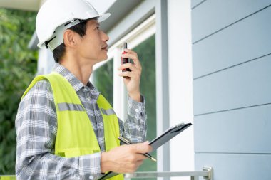 inspector or engineer is inspecting construction and quality assurance new house using a checklist. Engineers or architects or contactor work to build the house before handing it over to the homeowner