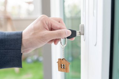 Evin kilidini açmak için ev sahibi anahtarı kapıya takılı. Kira ve satış için ikinci el ev. Sahibi el ile yeni ev için kapı ipoteğini açar, satın alır, satar, yeniler, yatırım, sahip, estat