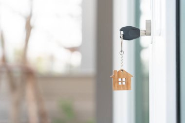 Landlord key for unlocking house is plugged into the door. Second hand house for rent and sale. keychain is blowing in the wind. mortgage for new home, buy, sell, renovate, investment, owner, estate