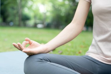 Kadın parkta meditasyon yapıyor. Sabahları egzersiz yapan Asyalı bir kadın. denge, dinlenme, rahatlama, sakinlik, sağlık, mutluluk, rahatlama, sağlıklı yaşam tarzı, stresi azaltma, huzur, tutum.