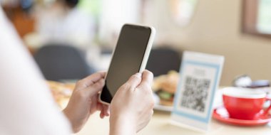 Woman use smartphone to scan QR code for order menu in cafe restaurant with a digital delivery. Choose menu and order accumulate discount. E wallet, technology, pay online, credit card, bank app.