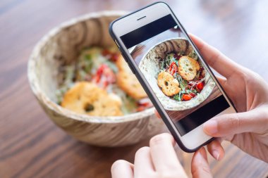 Restoran sahibi masadaki yemeklerin fotoğrafını çekiyor ve web sitesine yüklemek için akıllı telefon kullanıyor. Çevrimiçi gıda dağıtımı, sipariş servisi, nüfuz, gözden geçirme, sosyal medya, paylaşım, pazarlama, içişleri