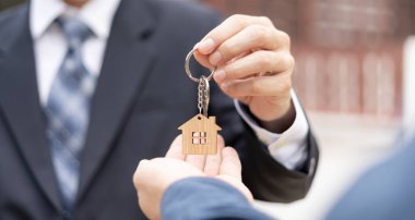 Kira, kiralama ve ev satma. Emlakçının elinde yeni sahibinin anahtarı var. kira, satış, kredi finans, sigorta, satıcı, dağıtıcı, taksit, satın alma, satma, taşınma