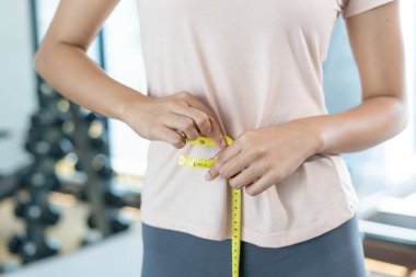 Diyet ve diyet. Güzel, ince kadın vücut ölçüsü. Spor elbiseli bir kadın sağlıklı yaşam için kilo verme hedefine, zayıflığa, ince belliye, beslenme uzmanına ulaşır..