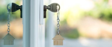 Landlord key for unlocking house is plugged into the door. Second hand house for rent and sale. keychain is blowing in the wind. mortgage for new home, buy, sell, renovate, investment, owner, estate