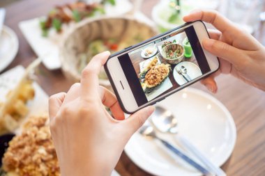 Restoran sahibi masadaki yemeklerin fotoğrafını çekiyor ve web sitesine yüklemek için akıllı telefon kullanıyor. Çevrimiçi gıda dağıtımı, sipariş servisi, nüfuz, gözden geçirme, sosyal medya, paylaşım, pazarlama, faiz