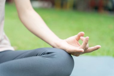 Kadın parkta meditasyon yapıyor. Sabahları egzersiz yapan Asyalı bir kadın. denge, dinlenme, rahatlama, sakinlik, sağlık, mutluluk, rahatlama, sağlıklı yaşam tarzı, stresi azaltma, huzur, tutum.