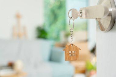 Moving house, relocation. The key was inserted into the door of the new house, inside the room was a cardboard box containing personal belongings and furniture. move in the apartment or condominium