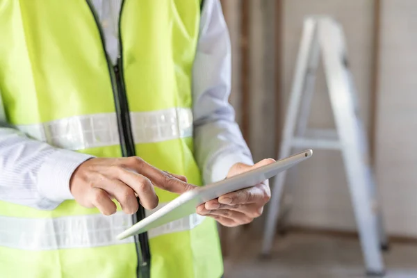 inspector or engineer is inspecting construction and quality assurance new house using a tablet. Engineers or architects or contactor work to build the house before handing it over to the homeowne