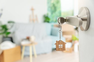 Moving house, relocation. The key was inserted into the door of the new house, inside the room was a cardboard box containing personal belongings and furniture. move in the apartment or condominium