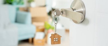 Taşınmak, taşınmak. Anahtar yeni evin kapısına yerleştirilmiş, odanın içinde kişisel eşyalar ve mobilyalar içeren bir karton kutu vardı. Daireye gir, afiş.