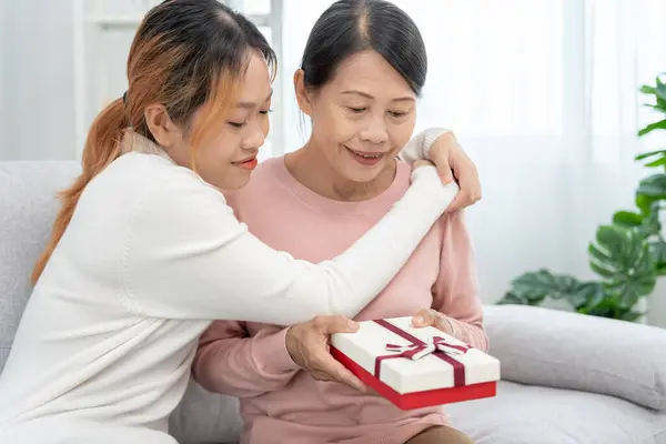 Mother day, cute asian teen girl give gift box to mature middle age mum. Love, kiss, care, happy smile enjoy family time. celebrating special occasion, happy birthday, happy new years, merry Christmas