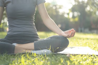 Kadın parkta meditasyon yapıyor. Sabahları egzersiz yapan Asyalı bir kadın. denge, dinlenme, rahatlama, sakinlik, sağlık, mutluluk, rahatlama, sağlıklı yaşam tarzı, stresi azaltma, huzur, tutum.