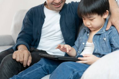 Küçük çocukla tablet kullanarak öğretmencilik oynayan mutlu bekar baba. Aile evde mutlu ve heyecanlı. Baba oğul birlikte vakit geçiriyorlar, iyi baba, bağımlılık düzelt, kontrol et.