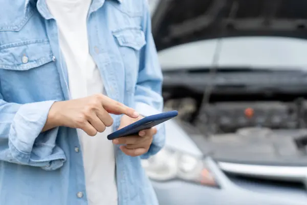 breakdown, broken car, repair. Woman uses mobile phone check insurance premiums through application due to car accident . Find garage to get car fixed during country tour, waiting for help, emergency.
