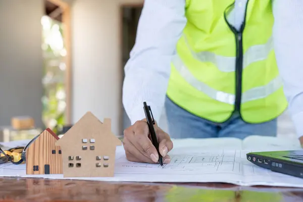 inspector or engineer is inspecting construction and quality assurance new house using a blue print. Engineer or architects or contactor work to build the house before handing it over to the homeowner