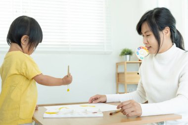 Mutlu Asyalı anne küçük kız için boya öğreniyor. Komik aile evde mutlu ve heyecanlı. Anne ve kızı birlikte vakit geçiriyorlar. Tatil, Etkinlik