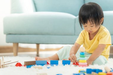 Mutlu Asyalı çocuk oyun oynuyor ve oyuncak bloklarını öğreniyor. Çocuklar evde çok mutlu ve heyecanlı. Çocuk oyun, etkinlik, gelişme ve dikkat eksikliği hiperaktivite bozukluğuyla çok iyi vakit geçiriyor