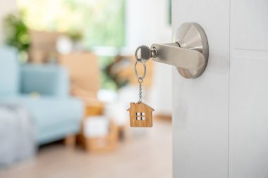 Moving house, relocation. The key was inserted into the door of the new house, inside the room was a cardboard box containing personal belongings and furniture. move in the apartment or condominium
