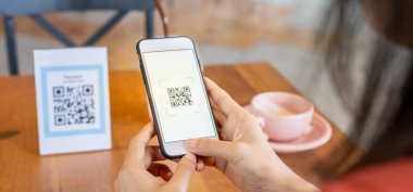 Woman use smartphone to scan QR code to pay in cafe restaurant with a digital payment without cash. Choose menu and order accumulate discount. E wallet, technology, pay online, credit card, bank app.