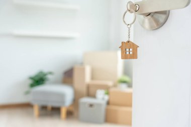 Moving house, relocation. The key was inserted into the door of the new house, inside the room was a cardboard box containing personal belongings and furniture. move in the apartment or condominium