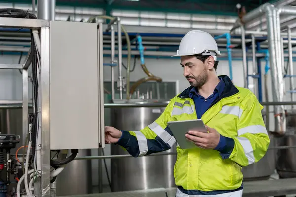 Güvenlik kaskı takan mühendisler veya fabrika yöneticileri üretim hattındaki makineleri inceler. Kamu müfettişi makineyi kontrol et ve standardı karşılamak için sistemi test et. makine, bakım.