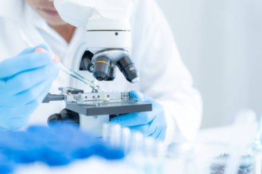 Bilimadamı ileri bilimsel laboratuvarda biyokimyasal örnekleri analiz ediyor. Tıbbi profesyonel kullanım mikroskobu virüsün mikrobiyolojik gelişimini gösteriyor. Fen laboratuvarında biyoteknoloji araştırması.