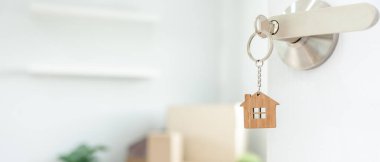 Moving house, relocation. The key was inserted into the door of the new house, inside the room was a cardboard box containing personal belongings and furniture. move in the apartment or condominium