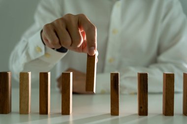 Domino 'yu elleri olan sigorta korur. İş adamı elleri iş krizinde domino taşlarının düşmesini durdurur. işletme risk denetimi ve planlama ve işletmeler sigorta işletmelerini önlemek için stratejiler.