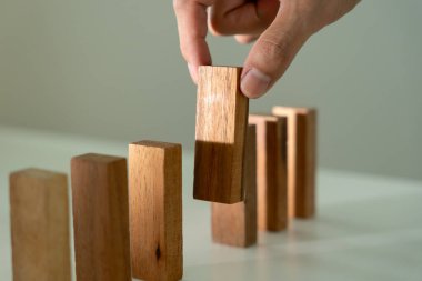 Domino 'yu elleri olan sigorta korur. İş adamı elleri iş krizinde domino taşlarının düşmesini durdurur. işletme risk denetimi ve planlama ve işletmeler sigorta işletmelerini önlemek için stratejiler.